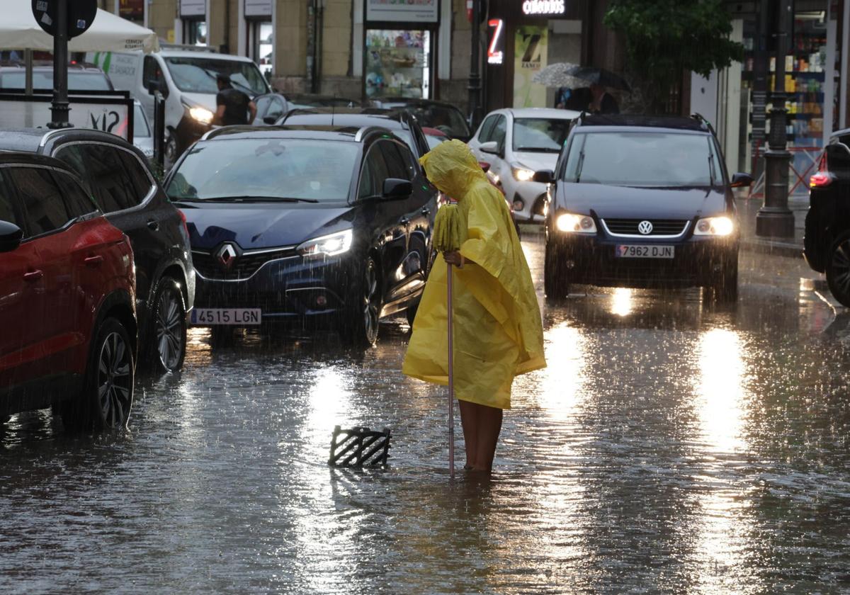 Una persona abre una alcantarilla para favorecer el achique de agua en Valladolid durante la tormenta del pasado marts.