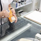 Una farmacéutica corta el código de barras de un medicamento.